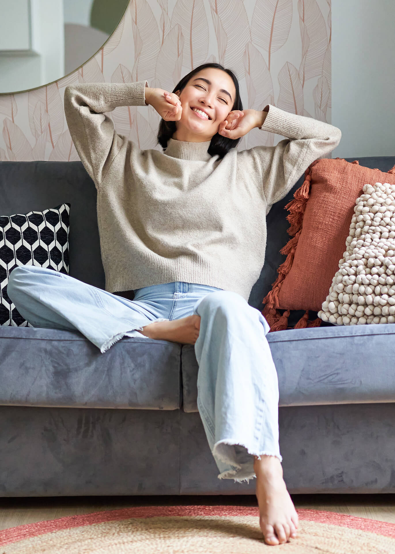 Portrait of happy asian woman feeling lazy, stretching on sofa and smiling pleased, relaxing at home, resting from work.
